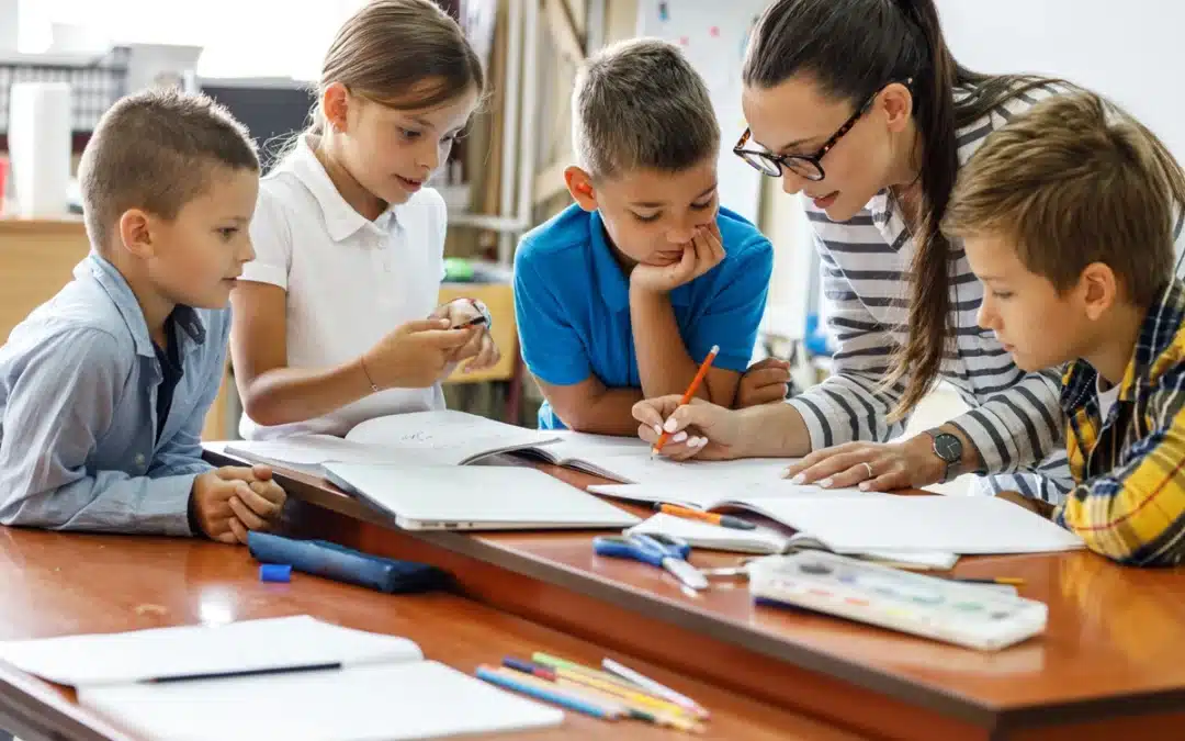 Teacher Working With Students At Desk